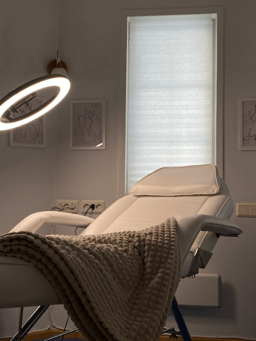 A cozy white bed with a neatly folded blanket on top. Perfect for a sugaring treatment. LuxBeauty By Helmi sugaring studio.
